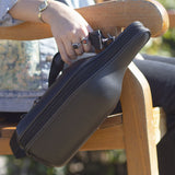 Lady holding CaddyO Leather wine tote in right hand while sitting in wood chair