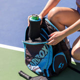 Person opening a sports bag on a tennis court with a iCube Wrapsulator  and pickle ball paddle.